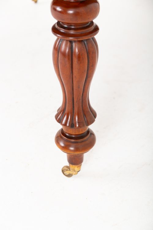 A Victorian mahogany extending dining table with two insertable leaves, fluted turned legs, and brass castors. View VI