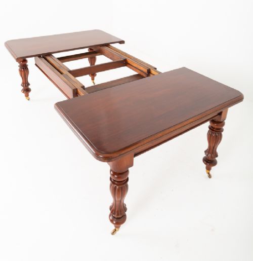 A Victorian mahogany extending dining table with two insertable leaves, fluted turned legs, and brass castors. View VIII