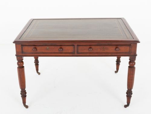 fig 1. A Victorian mahogany partners writing table featuring a green leather inset top, turned legs on brass castors, and drawers with wooden knob handles.