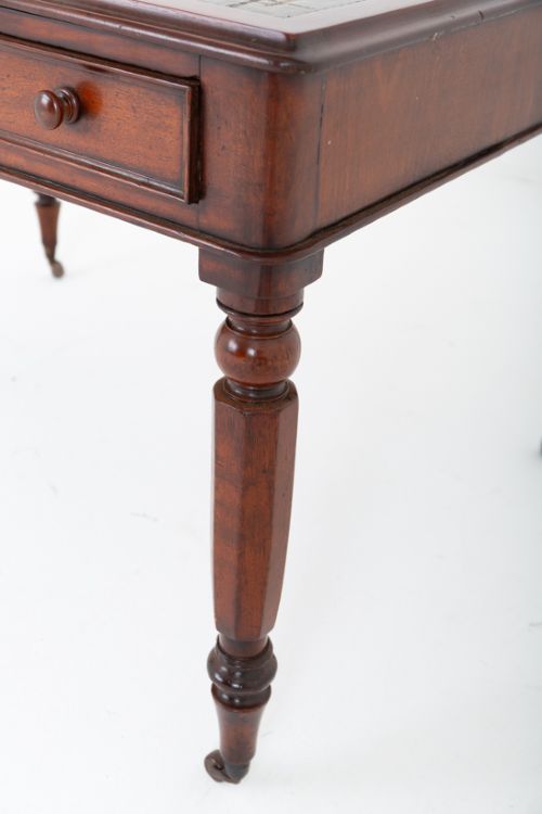 fig 2. A Victorian mahogany partners writing table featuring a green leather inset top, turned legs on brass castors, and drawers with wooden knob handles.