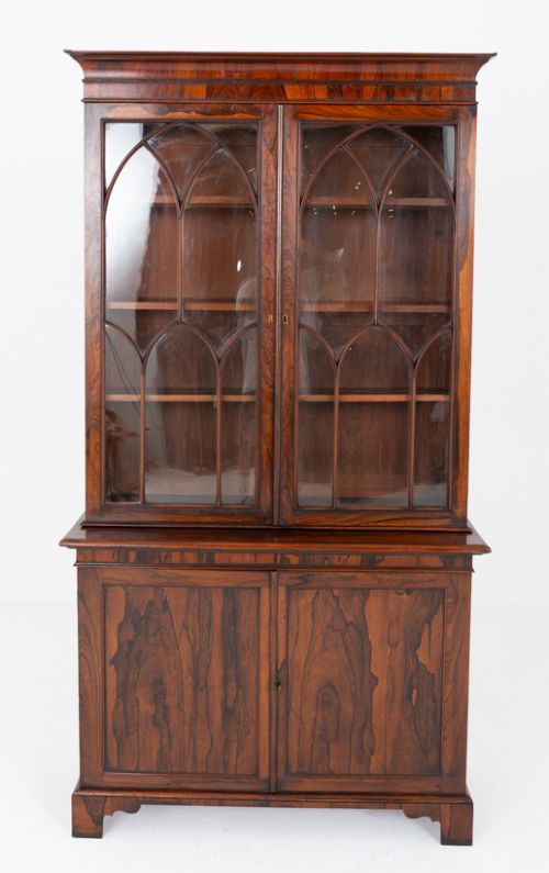 fig 1. A William IV rosewood glazed bookcase featuring Gothic arched glazing bars on the upper double doors above a two-door solid cabinet base.