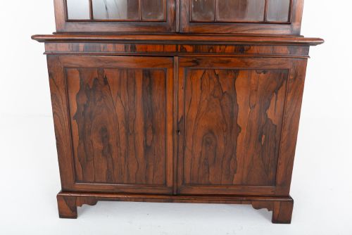 fig 2. A William IV rosewood glazed bookcase featuring Gothic arched glazing bars on the upper double doors above a two-door solid cabinet base.
