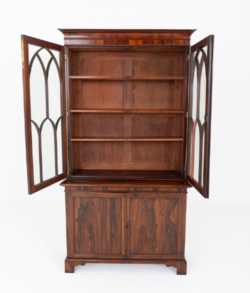 A William IV rosewood glazed bookcase featuring Gothic arched glazing bars on the upper double doors above a two-door solid cabinet base. View VI