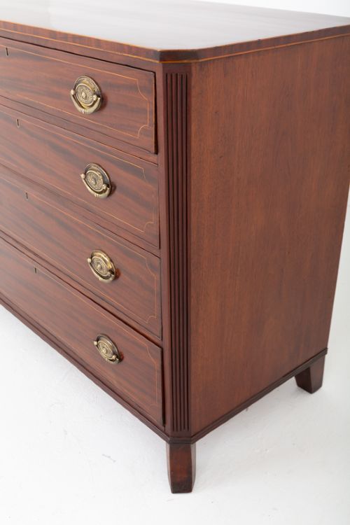 A Regency mahogany chest of four graduated drawers featuring brass oval backplate handles, reeded side pilasters, and splayed bracket feet. View V