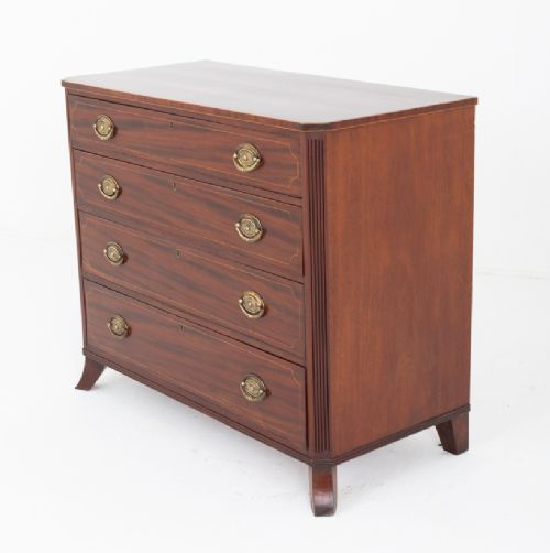 A Regency mahogany chest of four graduated drawers featuring brass oval backplate handles, reeded side pilasters, and splayed bracket feet. View X