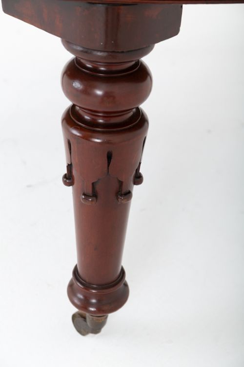 A William IV mahogany extending dining table with turned carved legs and brass castors set against a plain white background. View III
