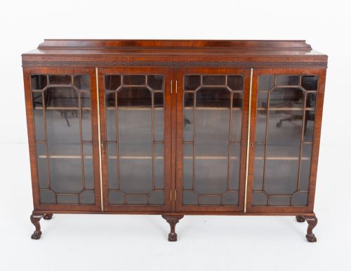 fig 1. A low mahogany four-door side cabinet featuring geometric astragal glazed glass panels and carved claw and ball feet.