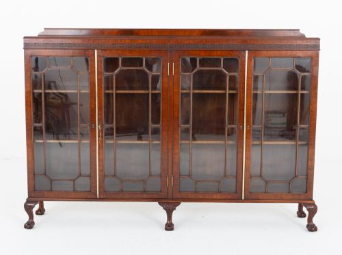 fig 2. A low mahogany four-door side cabinet featuring geometric astragal glazed glass panels and carved claw and ball feet.