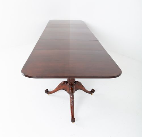 A large Regency style dark mahogany dining table featuring a three-pedestal base with carved splayed legs resting on brass castors. View XIII