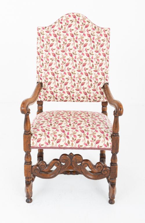 fig 1. A set of eight Jacobean style oak dining chairs featuring carved scroll stretchers, turned legs, and floral leaf patterned fabric upholstery.