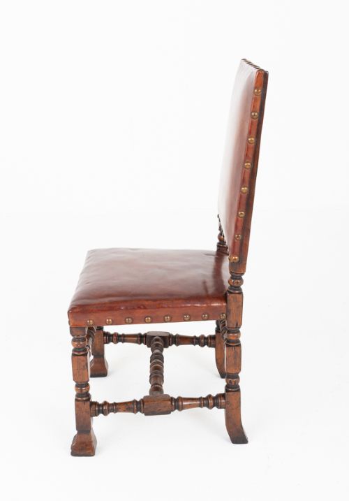 A set of ten brown leather upholstered oak dining chairs with brass studding and turned stretchers, including two carvers and eight side chairs. View V
