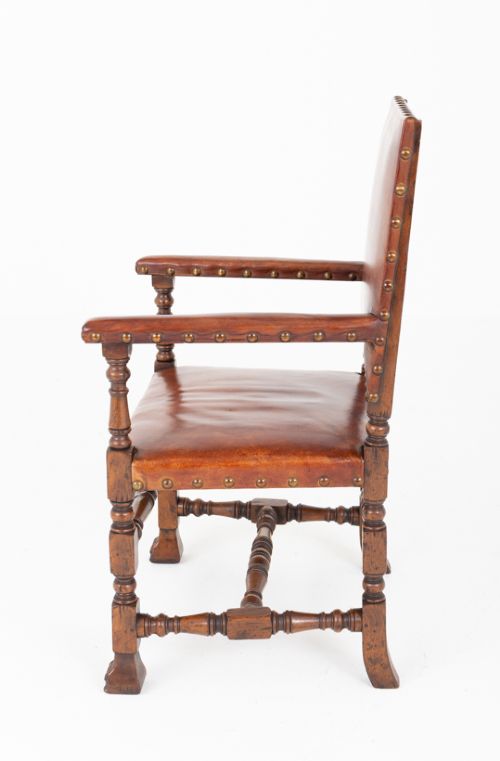 A set of ten brown leather upholstered oak dining chairs with brass studding and turned stretchers, including two carvers and eight side chairs. View IX