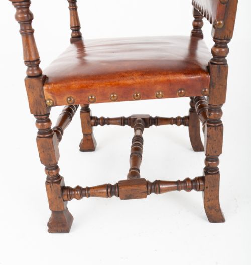 A set of ten brown leather upholstered oak dining chairs with brass studding and turned stretchers, including two carvers and eight side chairs. View X