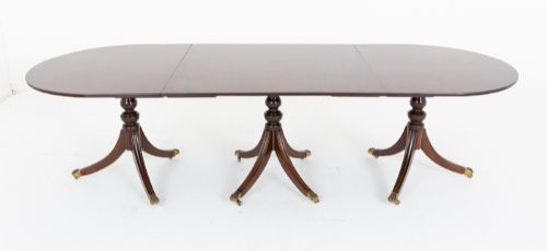 fig 1. A large Regency Revival dark mahogany three-pedestal dining table with reeded splayed legs and brass claw castors.