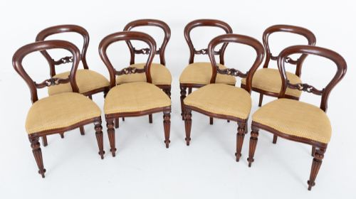fig 1. A set of eight Victorian style mahogany dining chairs with rounded balloon backs, carved mid-rails, gold upholstered seats, and fluted front legs.