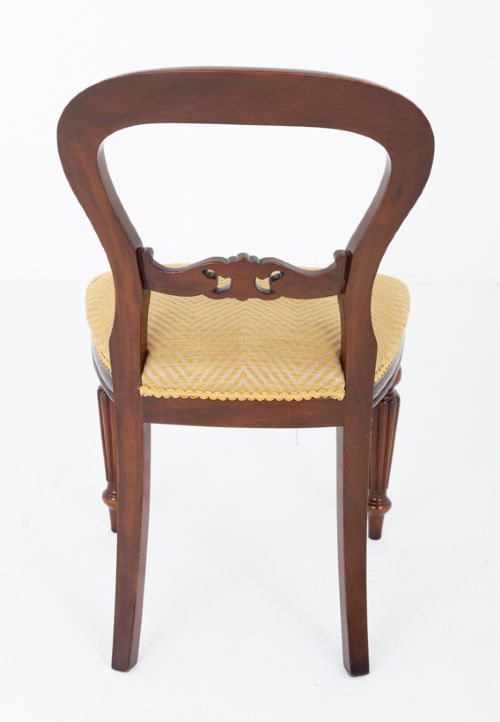 A set of eight Victorian style mahogany dining chairs with rounded balloon backs, carved mid-rails, gold upholstered seats, and fluted front legs. View VII