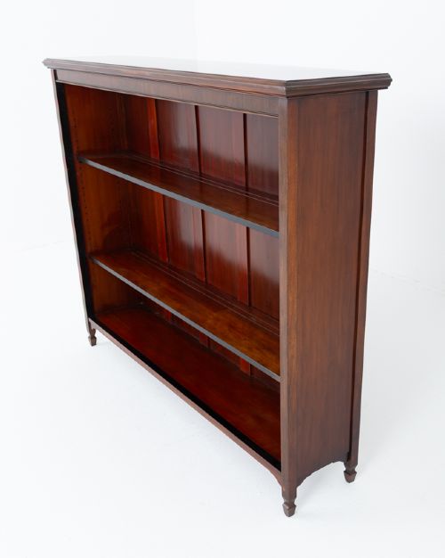 A wide Victorian open mahogany bookcase featuring a panelled back, two horizontal shelves, and turned feet. View III