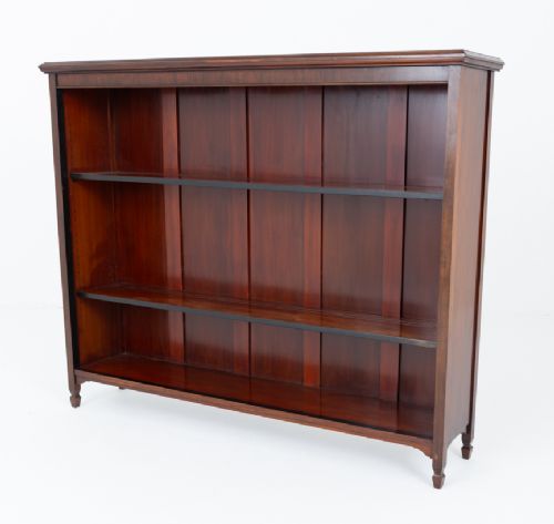 A wide Victorian open mahogany bookcase featuring a panelled back, two horizontal shelves, and turned feet. View IV