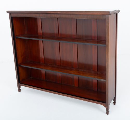 A wide Victorian open mahogany bookcase featuring a panelled back, two horizontal shelves, and turned feet. View VI