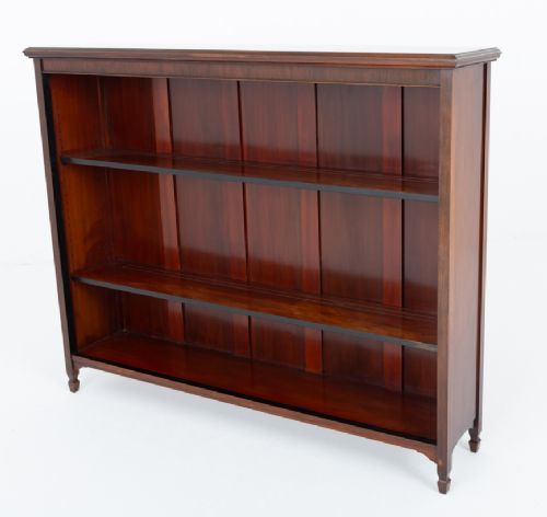A wide Victorian open mahogany bookcase featuring a panelled back, two horizontal shelves, and turned feet. View VII