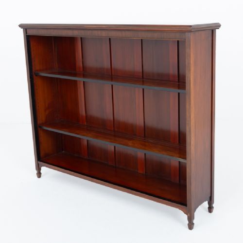A wide Victorian open mahogany bookcase featuring a panelled back, two horizontal shelves, and turned feet. View IX