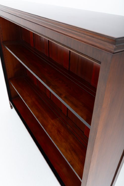 A wide Victorian open mahogany bookcase featuring a panelled back, two horizontal shelves, and turned feet. View X