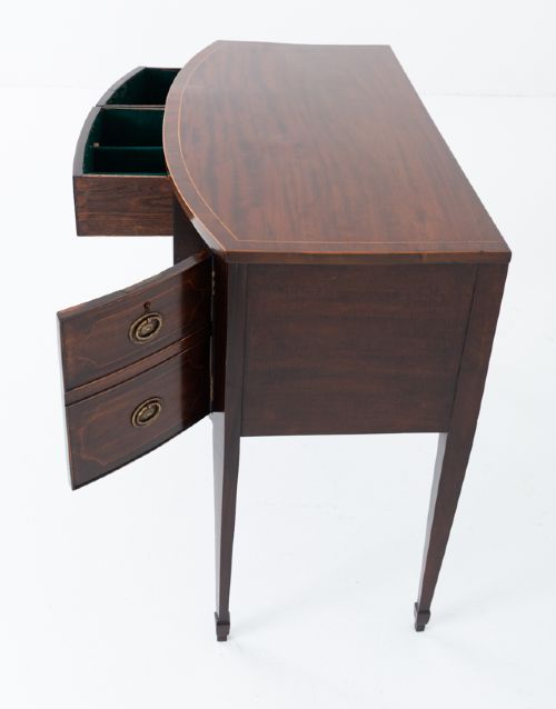 An antique Georgian bow-fronted mahogany sideboard with drawers featuring brass oval drop handles and tapered square legs. View V