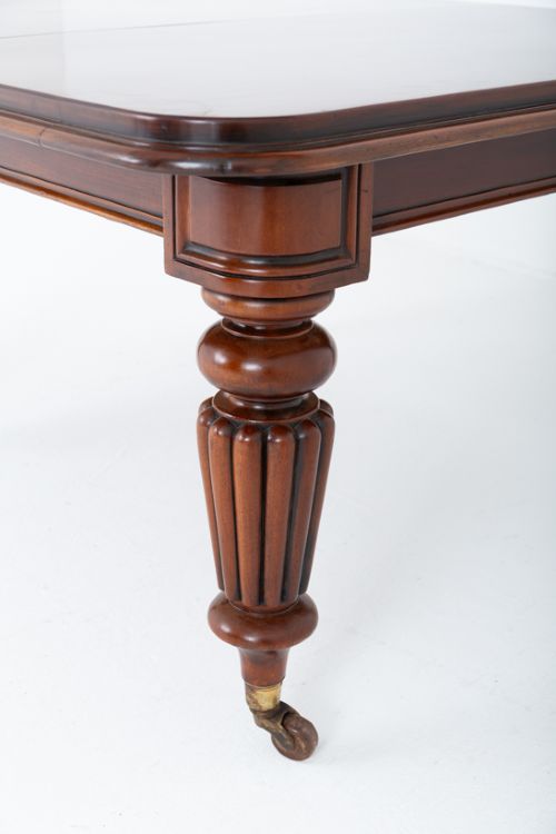 A William IV mahogany extending dining table with three additional leaves, standing on turned and reeded legs with brass castors. View IV