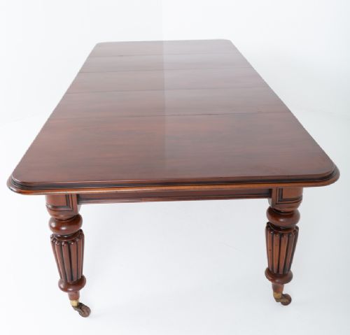 A William IV mahogany extending dining table with three additional leaves, standing on turned and reeded legs with brass castors. View IX