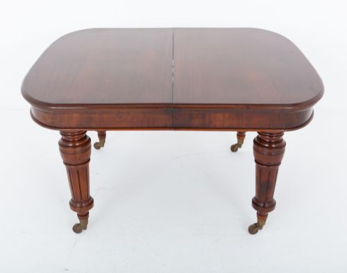 fig 1. A Victorian mahogany extending dining table with two removable extension leaves, turned fluted legs, and brass castors.