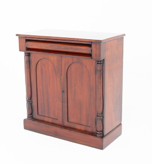 A Victorian mahogany side cabinet featuring two arched panel doors, turned side columns, a top frieze drawer, and a solid plinth base. View IV
