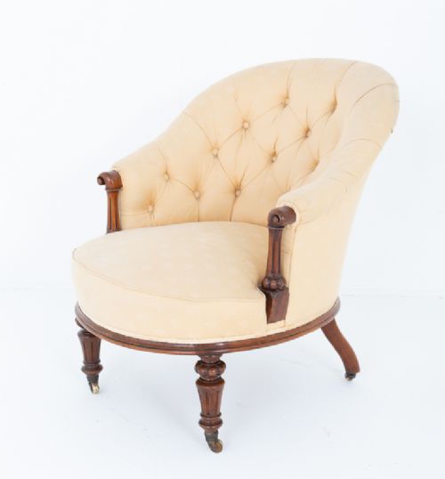 A Victorian deep buttoned tub chair upholstered in cream fabric, set on turned mahogany legs with brass castors. View V