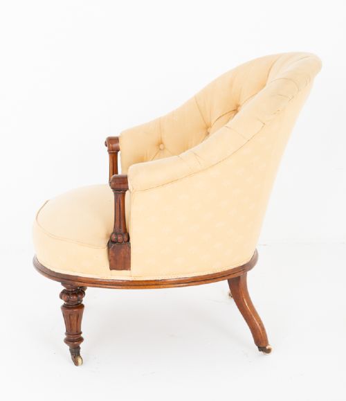 A Victorian deep buttoned tub chair upholstered in cream fabric, set on turned mahogany legs with brass castors. View VI