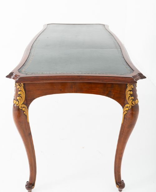 A mahogany centre writing table with cabriole legs, gilded rococo mounts on the frieze and knees, and a dark green leather inset surface. View IV