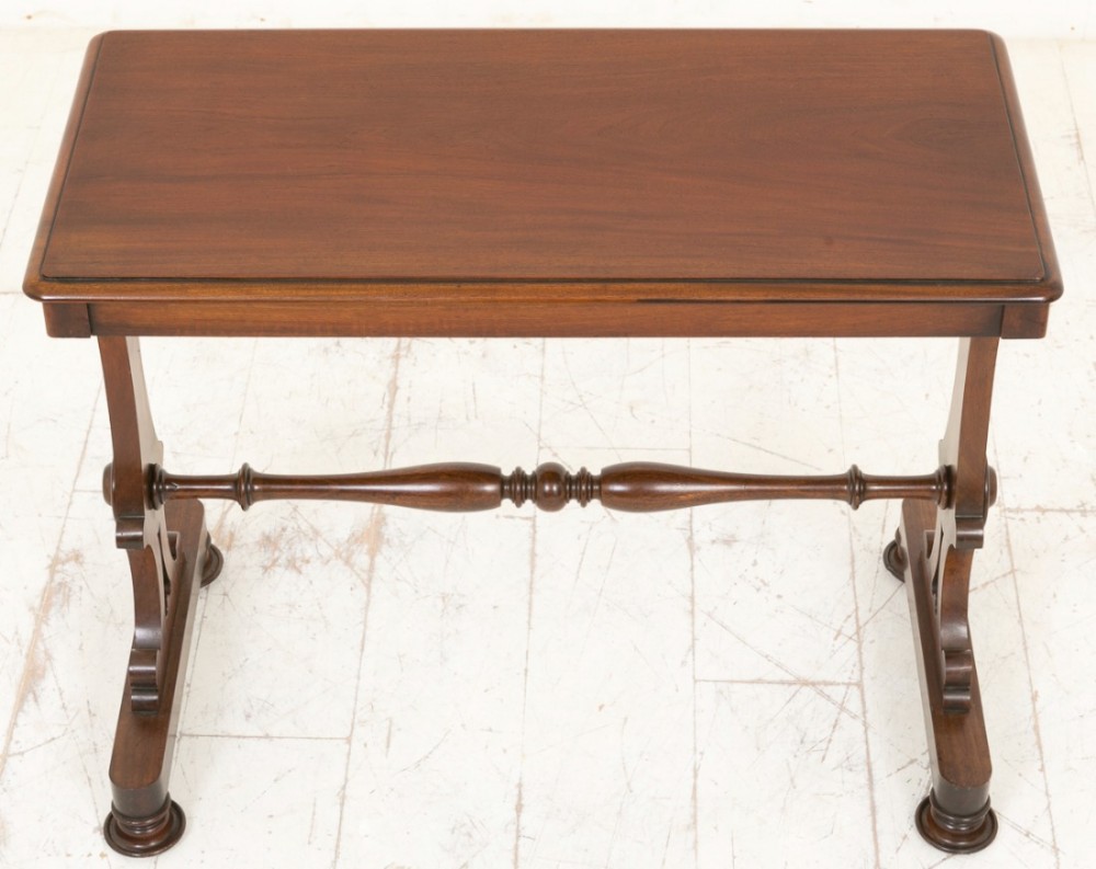 A rectangular Early Victorian mahogany centre table featuring turned stretcher rails and carved trestle supports.