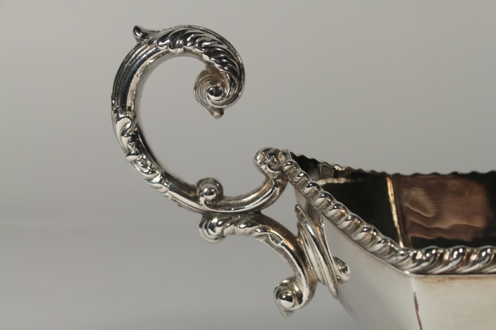 A pair of silver plated sauce boats with pedestal bases, scroll handles, and rope twist borders. View X