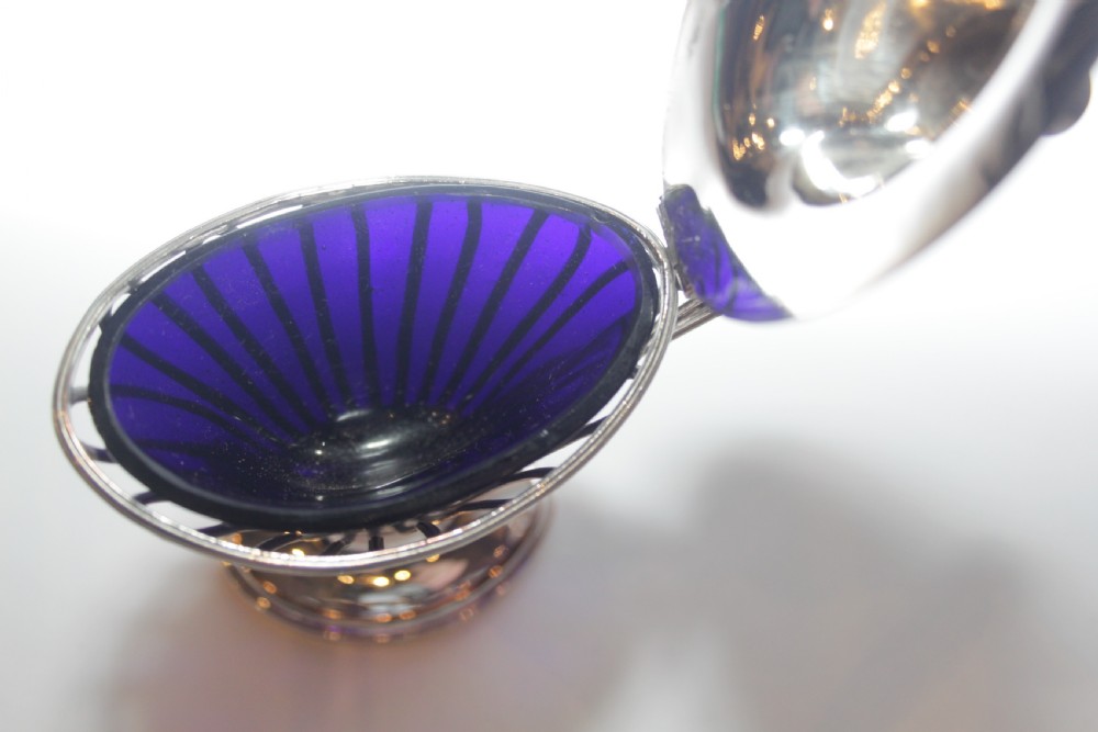 A silver-plated mustard pot with a pedestalled base, looped handle, conical lid, and removable cobalt blue glass liner. View VII
