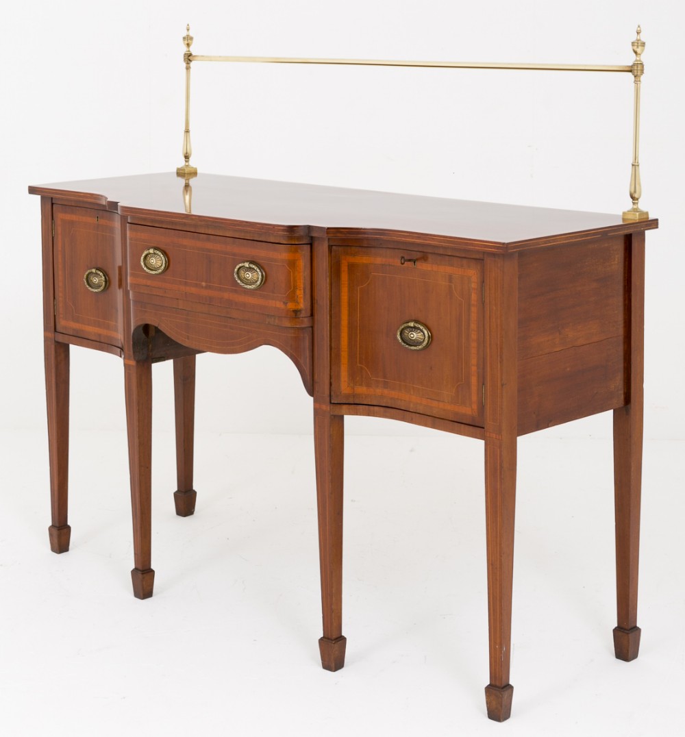 A mahogany Sheraton Revival sideboard featuring satinwood stringing, brass gallery rail, oval brass drop handles, and square tapered legs with spade feet.