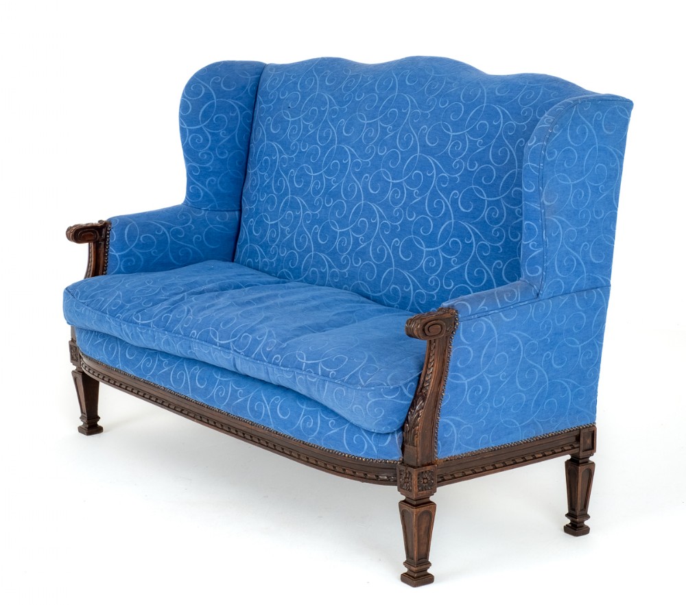 A French style mahogany settee featuring a carved wooden frame with fluted legs and high-backed blue patterned upholstery.