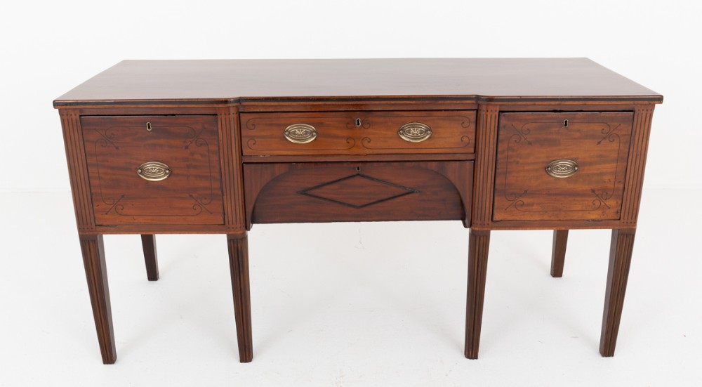 A Regency mahogany sideboard featuring fine string inlay, fluted square tapered legs, brass oval handles, and central drawers flanked by cupboards.