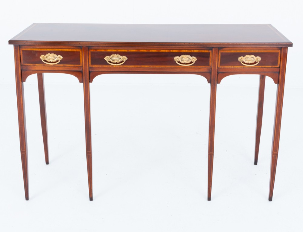 A Sheraton Revival mahogany server featuring three drawers with brass handles, decorative string inlay, arched spandrels, and four slender tapered legs. View II