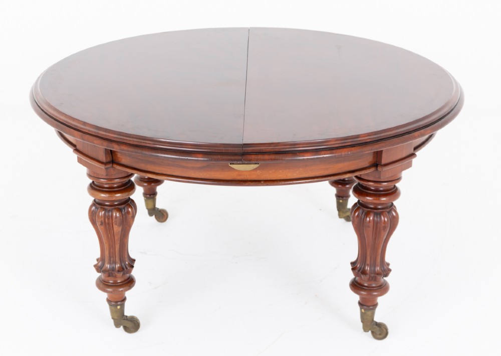 Large Victorian mahogany extending dining table featuring rounded ends, multiple removable leaves, turned fluted legs, and brass castors. View II