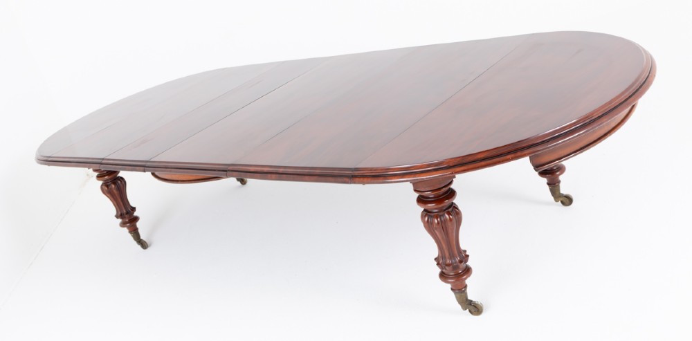 Large Victorian mahogany extending dining table featuring rounded ends, multiple removable leaves, turned fluted legs, and brass castors. View VIII