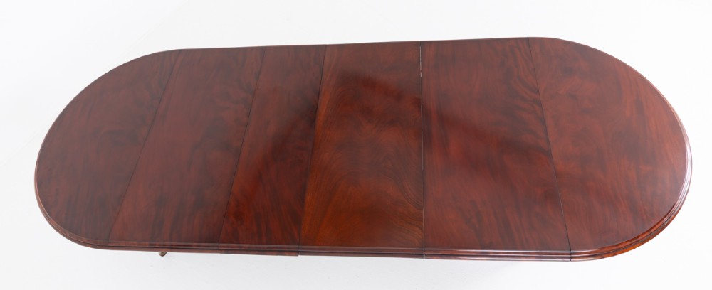 Large Victorian mahogany extending dining table featuring rounded ends, multiple removable leaves, turned fluted legs, and brass castors. View IX