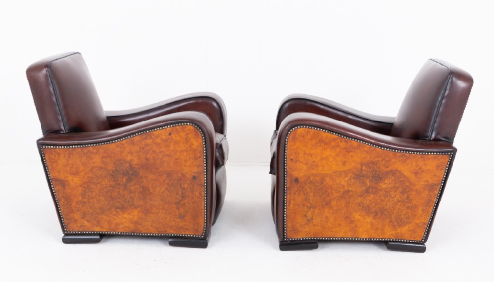 A pair of Art Deco club chairs upholstered in brown leather with burr walnut side panels and studded trim. View VI