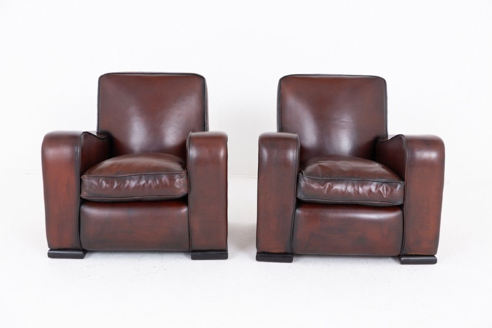 A pair of Art Deco club chairs upholstered in brown leather with burr walnut side panels and studded trim. View VIII