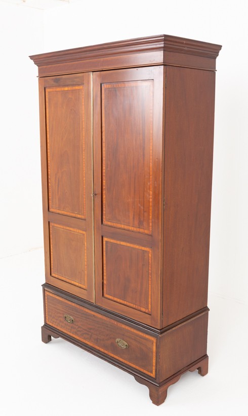 A tall Sheraton Revival mahogany two-door wardrobe featuring inlaid panelled doors, a lower base drawer, and bracket feet.