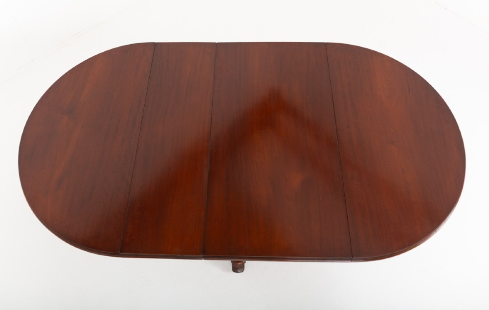 An antique Victorian mahogany extending dining table featuring an oval top, removable centre leaf, and a carved central pedestal base with splayed legs. View VI