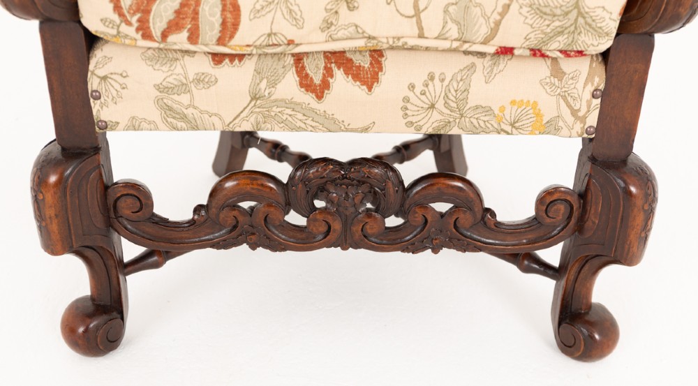 A three-piece Carolean style seating suite comprising a settee and two matching armchairs with woven cane backrests, carved scroll stretchers, and floral fabric seat cushions. View XI