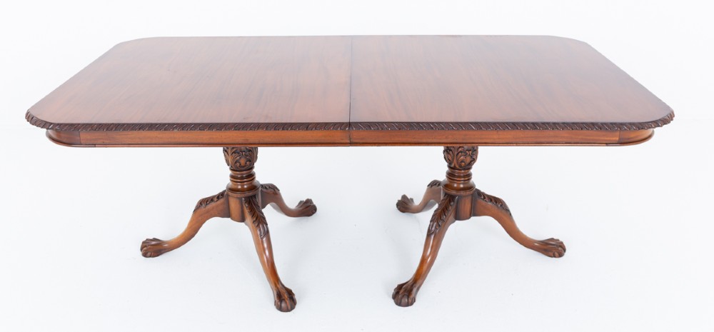 A Regency Revival twin-pedestal mahogany dining table featuring carved edging, turned support pillars, and splayed legs ending in carved feet. View II